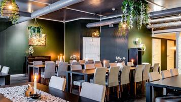 A conference room with multiple tables and chairs, a piano, and hanging plants.
