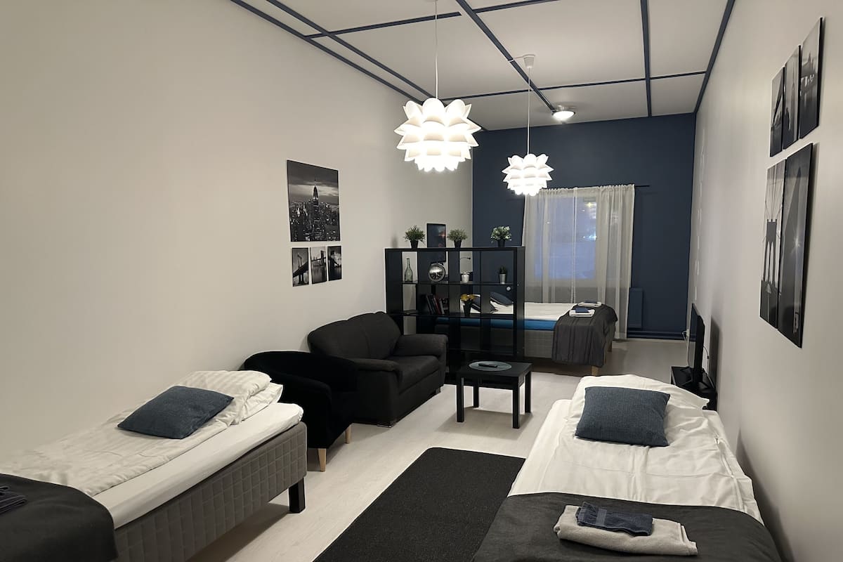 Un dormitorio moderno con dos camas individuales, un sofá, una mesita y una estantería.