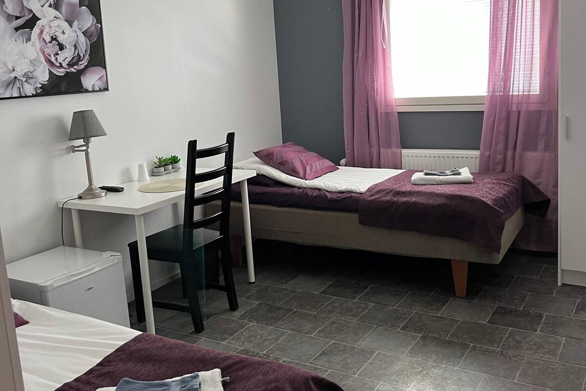 Una habitación pequeña con dos camas, un escritorio y una silla.