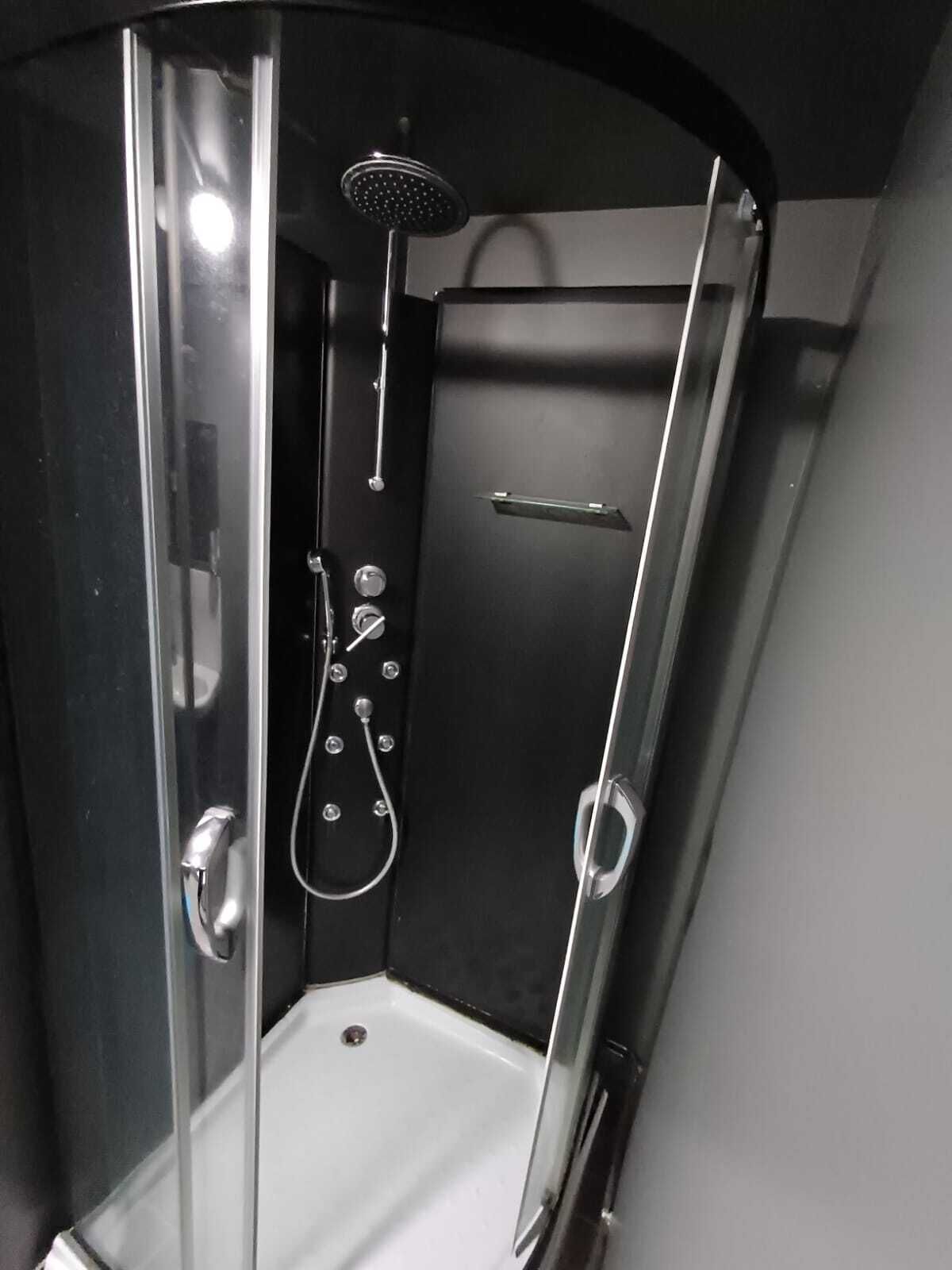 Une cabine de douche moderne dotée d’une porte en verre, d’un pommeau de douche à main et d’un robinet mural.
