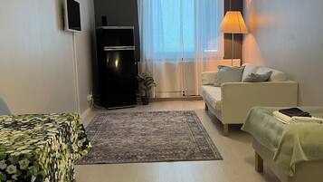 Una sala de estar moderna con un sofá, una mesita, un televisor, una lámpara y un ventanal con cortinas.