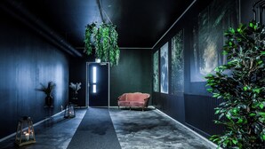 A hallway with a vintage red sofa, hanging plants, and framed pictures on the walls.