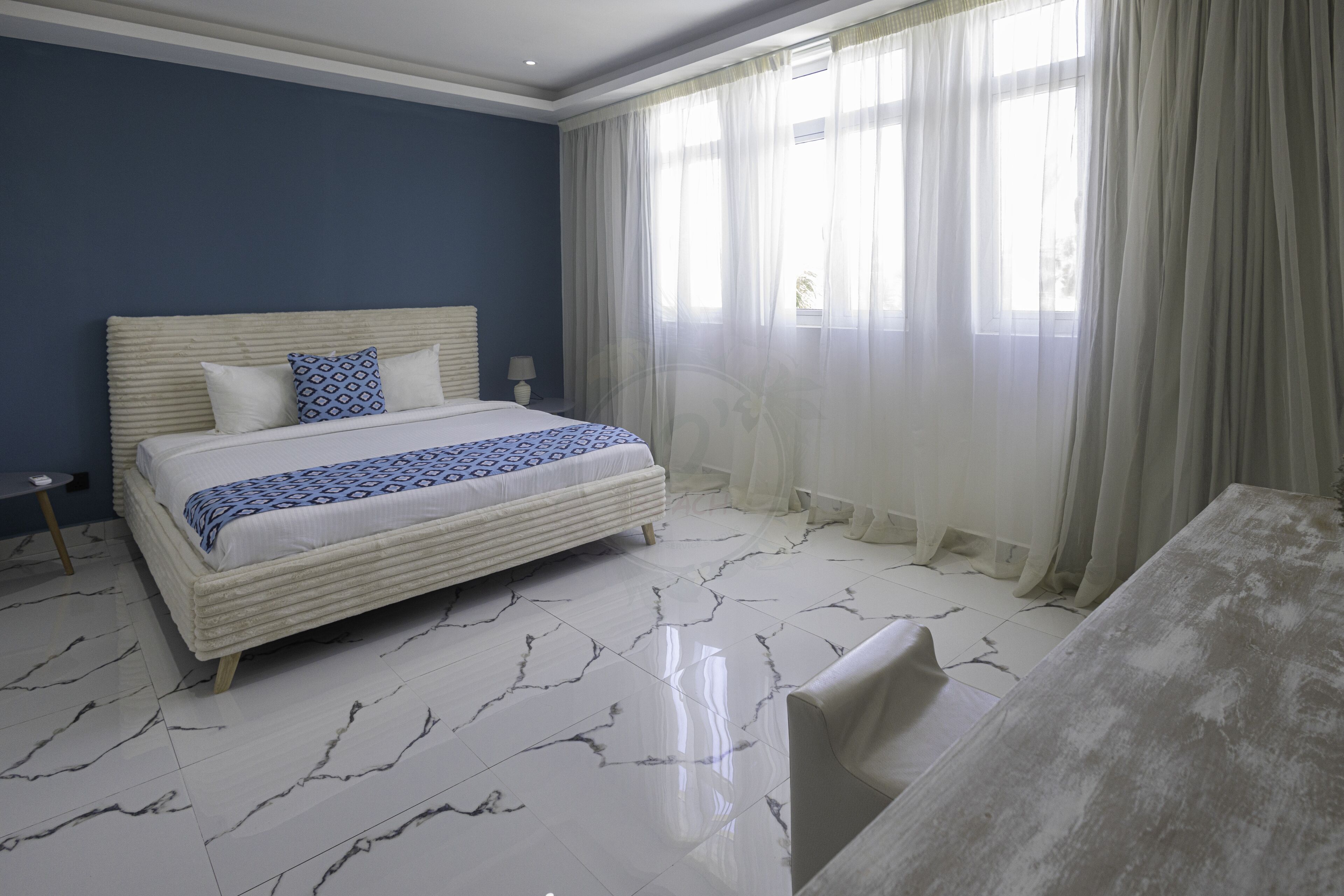 A bedroom with a bed, a bedside table, a lamp, and a window with curtains.