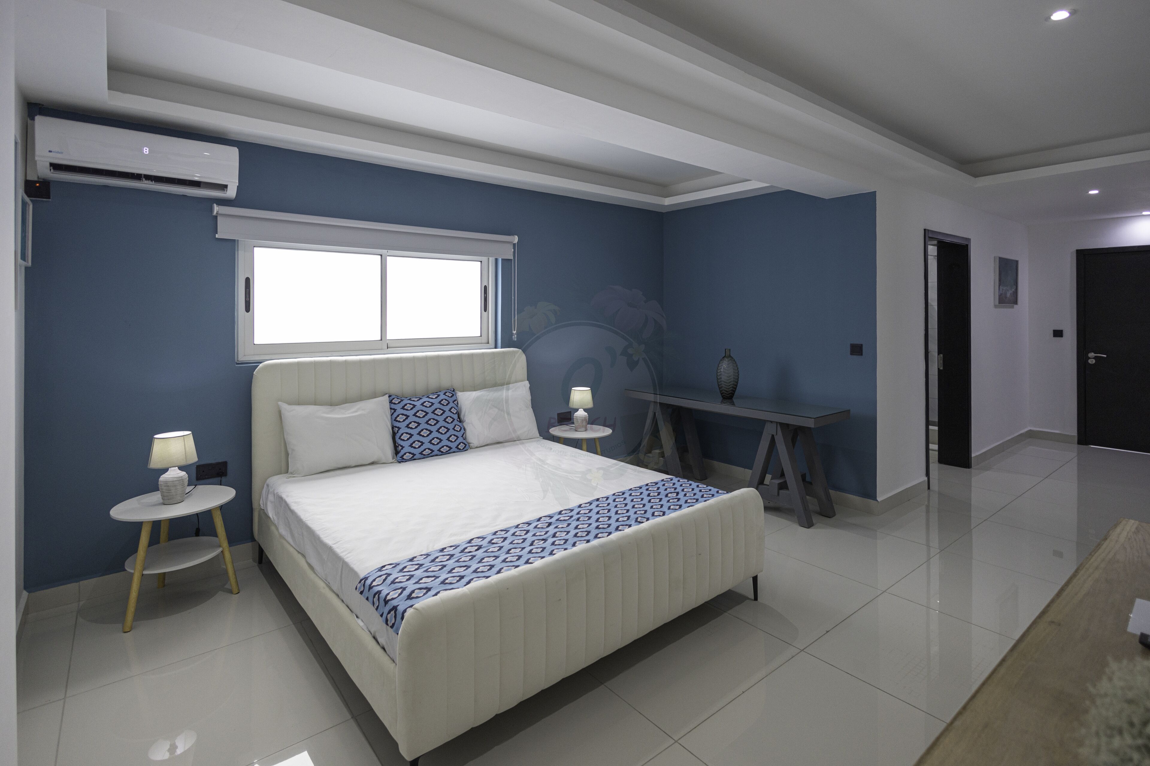 A bedroom with a bed, bedside tables, a lamp, a window, and a radiator.