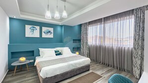 Un dormitorio moderno con cama, mesitas de noche, una silla y obras de arte en las paredes.