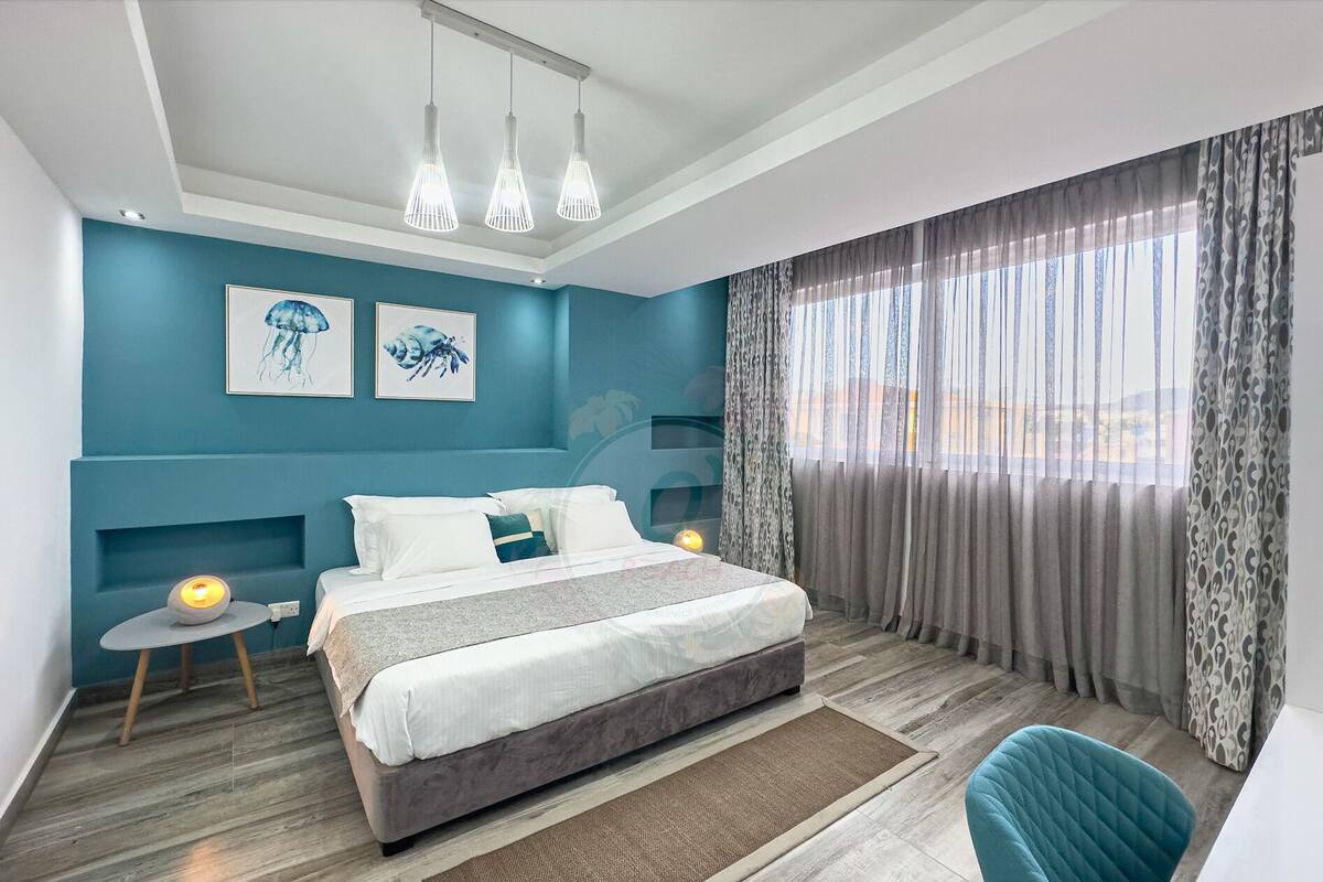 Ein modernes Schlafzimmer mit Bett, Nachttischen, einem Sessel und Bildern an den Wänden.