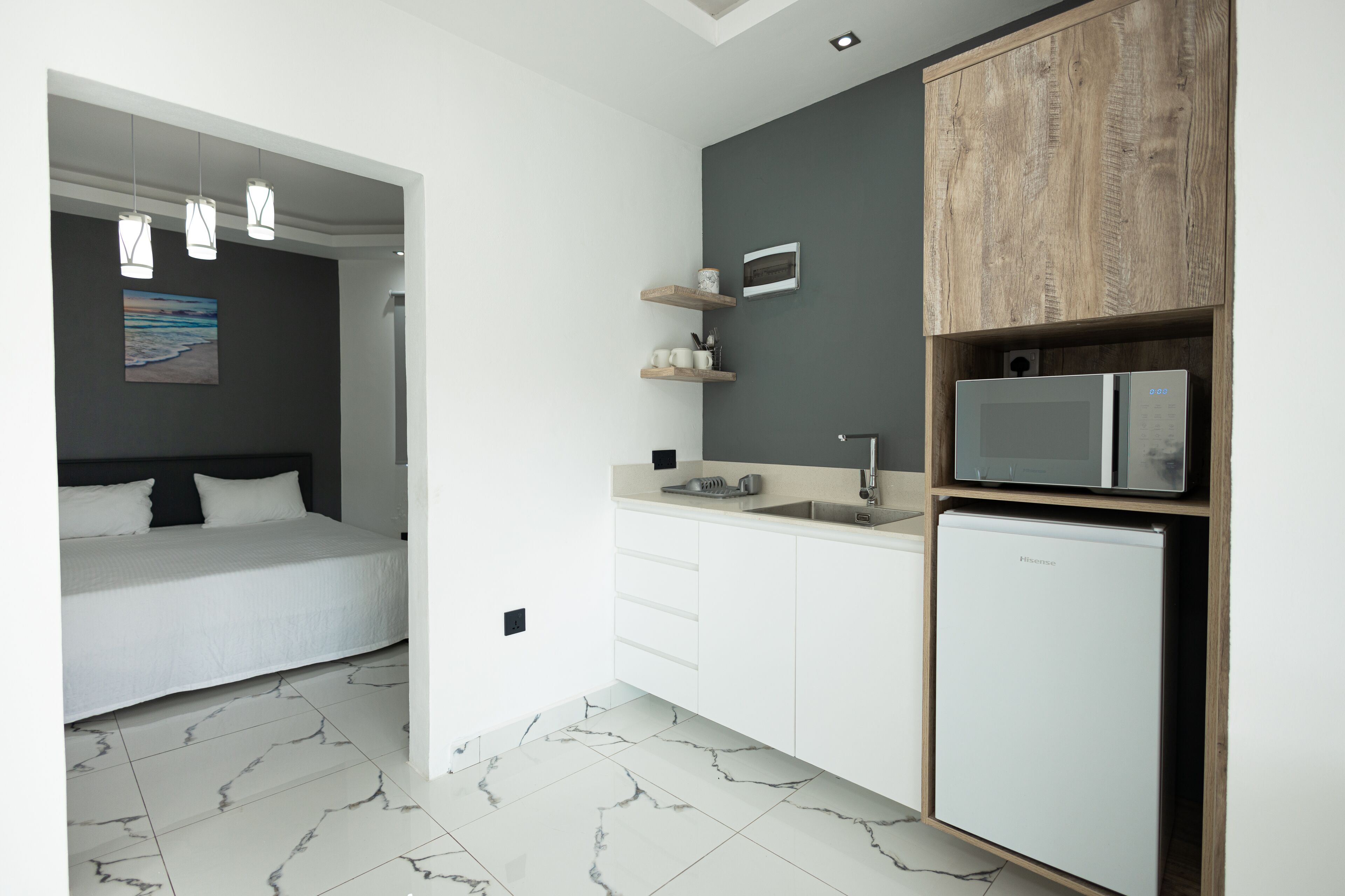 Et moderne hotelværelse med en seng, et lille tekøkken og et badeværelse.
