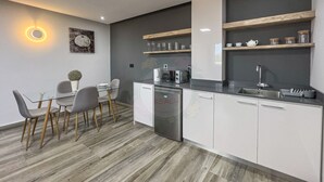 Una cocina moderna con lavavajillas, un fregadero y un comedor con mesa y sillas de vidrio.