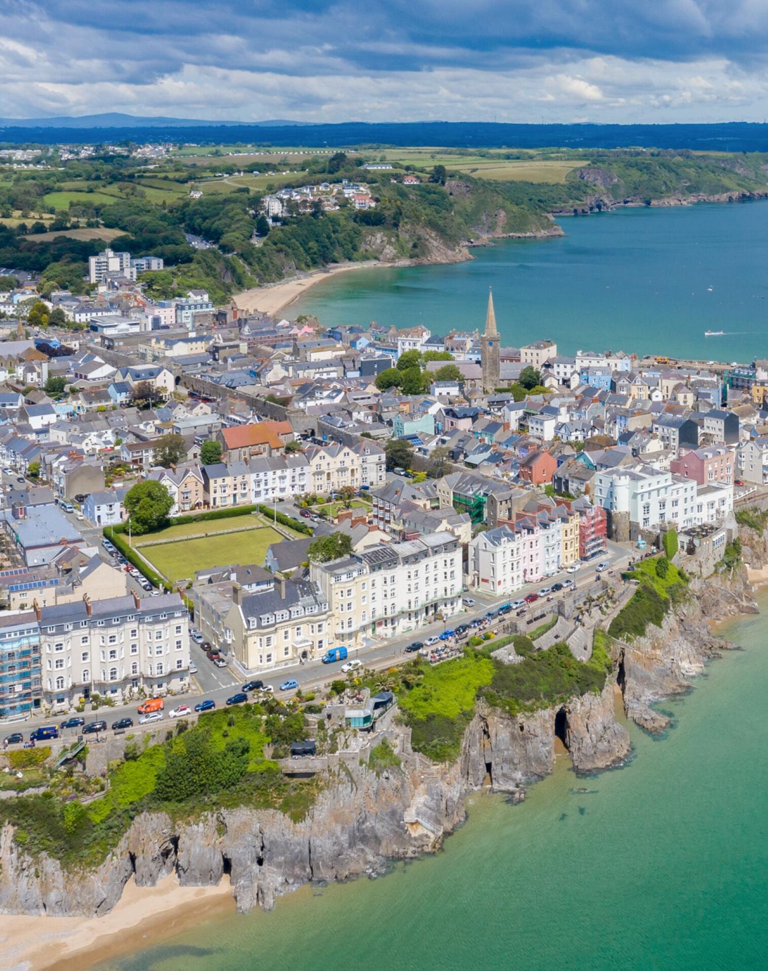 A coastal town with a prominent church, a sandy beach, and a rocky coastline.