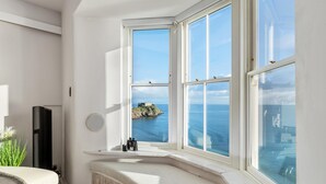A room with a large bay window overlooking the sea, a built-in bench, and a small round mirror on the wall. - Min Y Mor - Breathtaking Sea Views (Tenby)