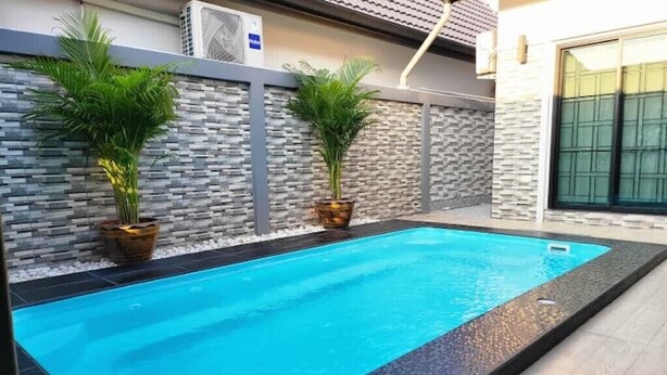 Ein Schwimmbecken mit einer Steinwand und zwei Blumentöpfen.