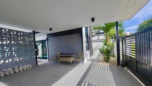 Eine moderne Außenpatio mit Esstisch und Stühlen, einer Zierwand und Blick auf ein Wohngebäude.