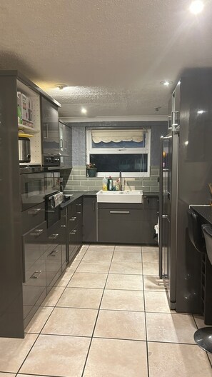 Cocina moderna con armarios oscuros, horno empotrado y ventana con un adornado frente.