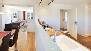 Una cocina moderna con una isla central, un comedor con sillas y una sala de estar con un sofá.