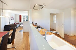 Une cuisine moderne avec un îlot central, un coin repas avec des chaises et un salon avec un canapé.