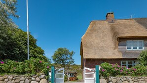 Una casa tradicional con techo de paja, pared de piedra y una puerta de madera.