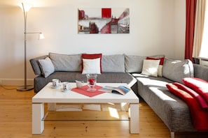 A modern living room with a sofa, a coffee table, and a floor lamp. - Herzlich Willkommen im Ferienhaus Haus am Heidetal (List)