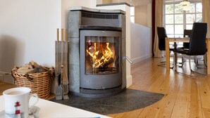 Una sala de estar moderna con chimenea de piedra, una mesa de comedor con sillas y una mesa baja con un libro.