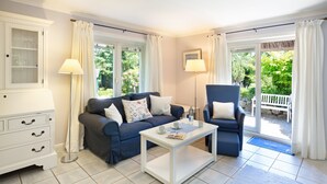 Une pièce comprenant un canapé, un fauteuil et une table basse. On y trouve également un meuble avec des tiroirs et une lampe.
