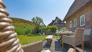 Une terrasse avec des meubles en osier, une table et un livre.