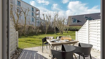 Een terras buiten met een tafel, stoelen, een boek en een glas water.