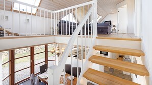 Un loft espacioso con escalera de madera, zona de comedor con vistas y un rincón de estar acogedor.