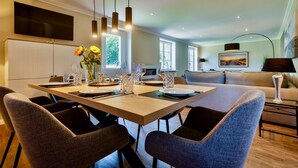 A modern dining area with a large table, multiple chairs, and pendant lighting.