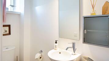 Une salle de bain avec un lavabo blanc, un miroir, des toilettes et un tableau encadré au mur.