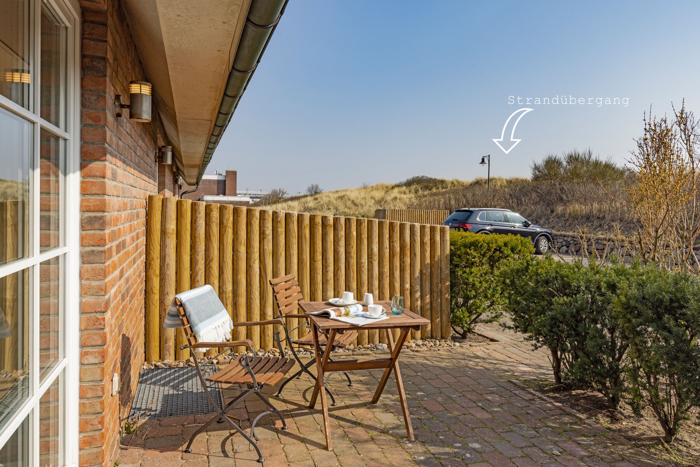 Een terras met een tafel gedekt voor twee personen, een stoel en een houten omheining.