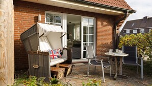 A patio with a wicker chair, a small table, and a bench.