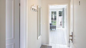A hallway with white walls, a gray rug, and a door leading to a patio area with outdoor furniture.