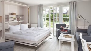 Ein Schlafzimmer mit einem Bett, einem Sessel, einer Couch, einem Tisch und einem Einbauschrank.