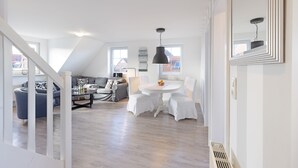 Un espacio habitable amplio con techo alto, una mesa de comedor con sillas, un sofá y una escalera.