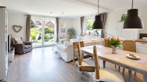 A spacious living area with a dining table, wicker chairs, and a sofa. - Herzlich Willkommen im Appartement Blickfang (List)