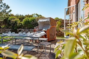 Enjoy a casual meal in a serene outdoor setting surrounded by lush greenery and a rustic stone wall.