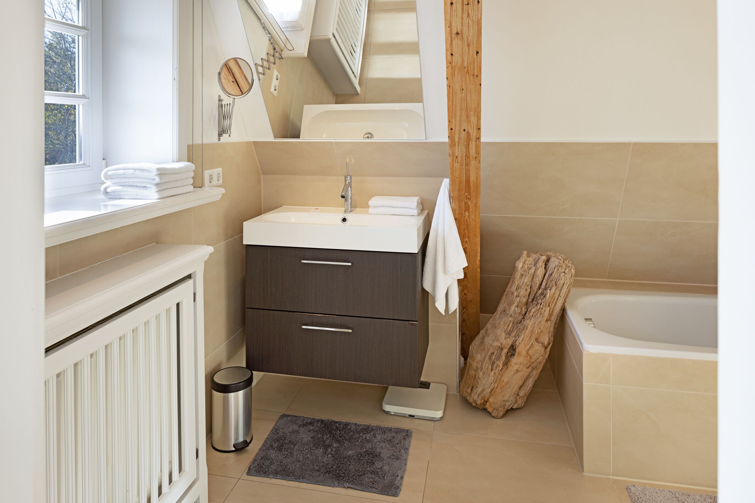 Une salle de bain moderne avec un lavabo blanc, un meuble-lavabo en bois foncé, une baignoire blanche et un grand miroir.