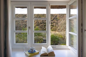 Quarto com uma grande janela com vista para uma paisagem ondulada.