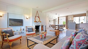 Un salón espacioso con chimenea, piso de madera y un comedor con mesa y sillas.