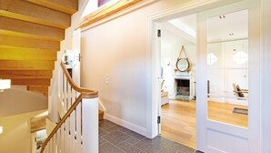 Una escalera con escalones de madera y barandillas blancas que conduce a una habitación con chimenea y un espejo en la pared.