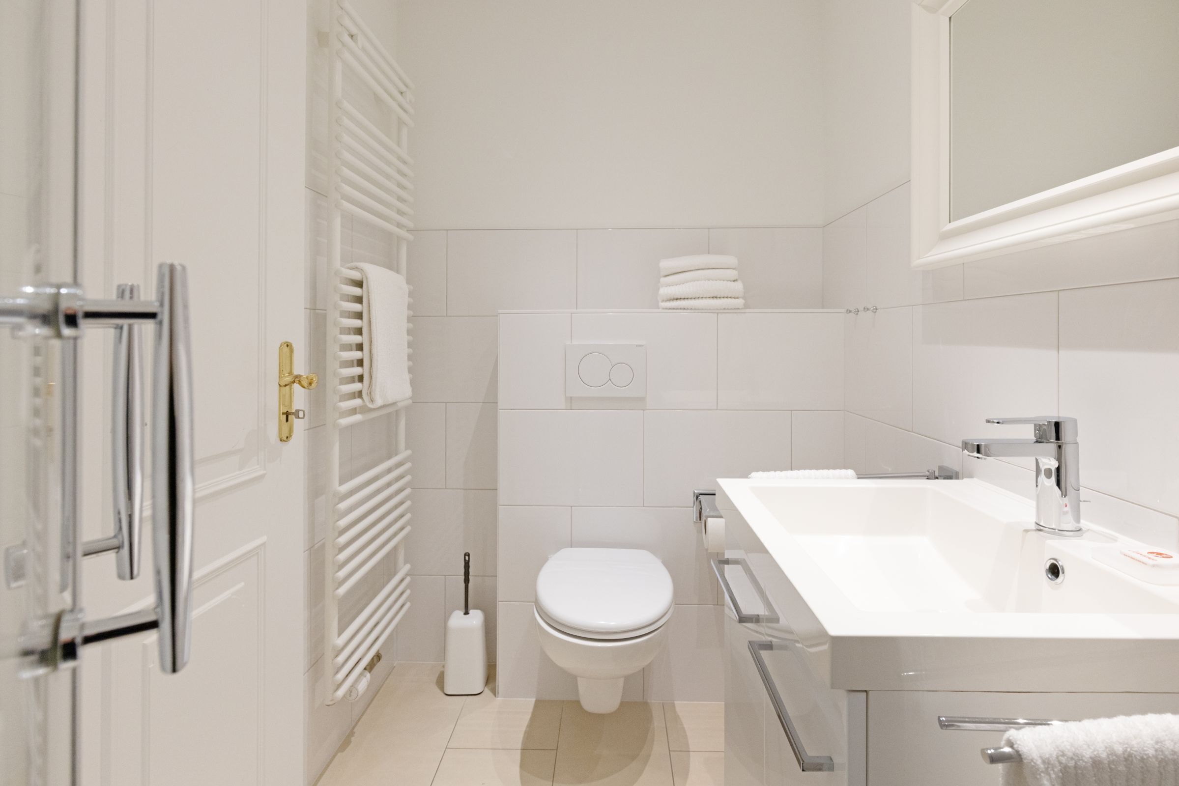 Un baño moderno con un lavabo blanco, un inodoro y un perchero para toallas.