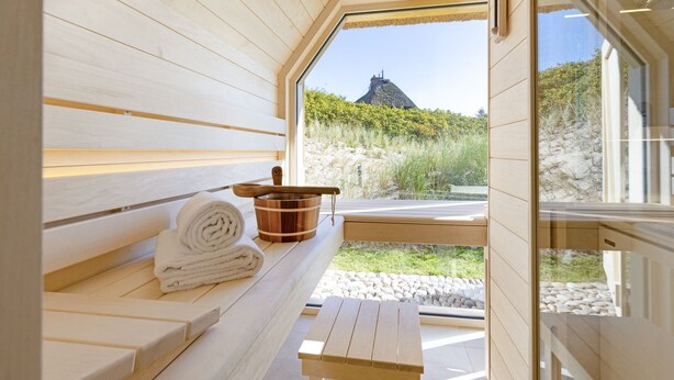 A sauna room with wooden benches, a wooden table, and a view of a mountain.