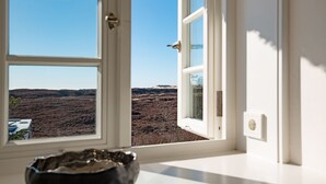 A room with a window offering a view of a barren landscape.