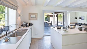 A modern kitchen with a central island, built-in appliances, and a view to a dining area.