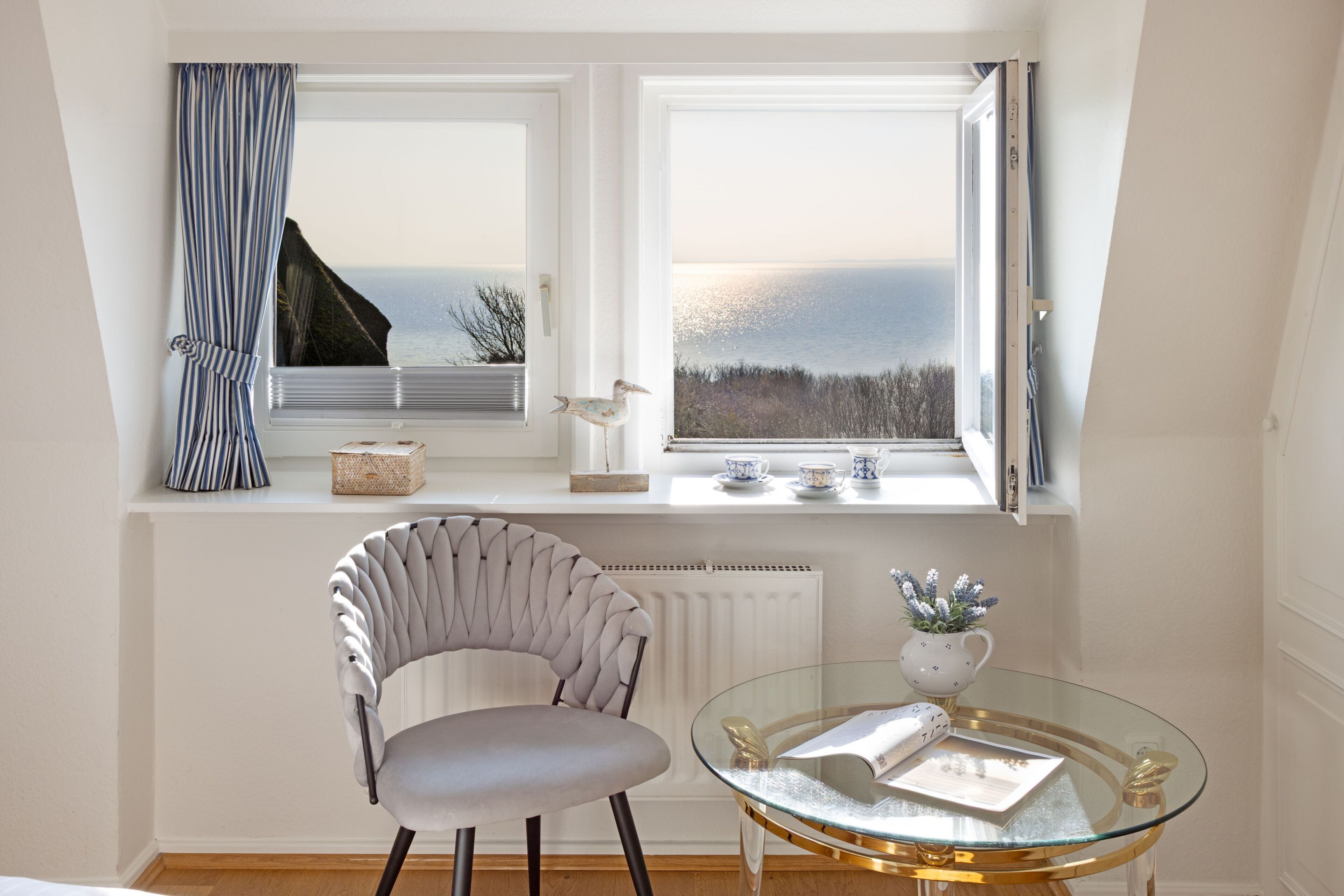 Ein Zimmer mit Meerblick, ein Sessel, ein Glastisch und eine Heizung.