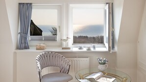Ein Zimmer mit Meerblick, ein Sessel, ein Glastisch und eine Heizung.
