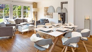 Una sala de estar moderna con zona de comedor, que incluye un conjunto de sofá, una mesa de comedor con sillas y una chimenea.