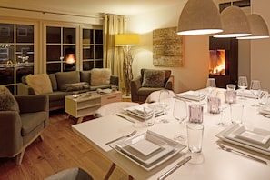 Un salon moderne avec un coin repas aménagé pour un repas. On y trouve un canapé, une table basse et une cheminée en arrière-plan.