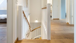 Una escalera con barandillas blancas y escalones de madera que conducen a una habitación con una cama.