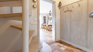 Una escalera conduce a un comedor con piso de ladrillo y mobiliario de madera.