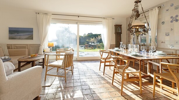 Un salón espacioso con una gran mesa de comedor, asientos cómodos y vistas al exterior.